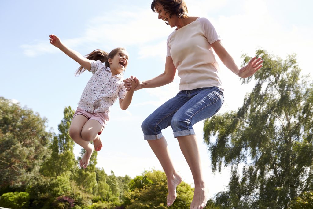 Mother And Daughter Bouncing On trampoline Together