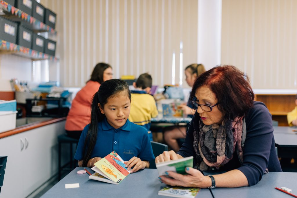 Teacher reading to a young adult. 