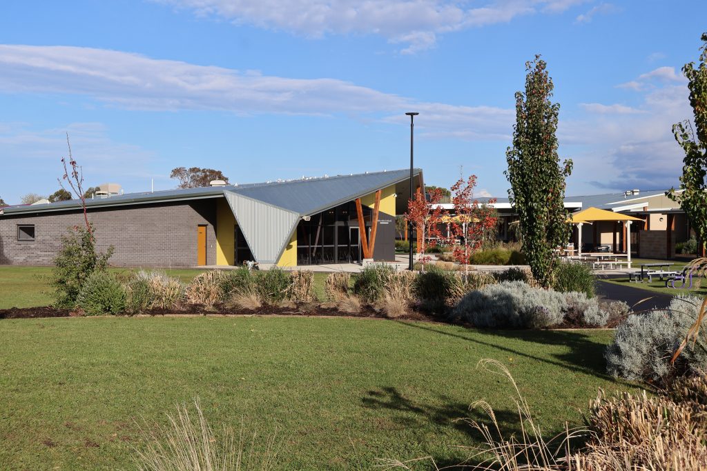 Photo of new School buildings with lawn and plants in the foreground.